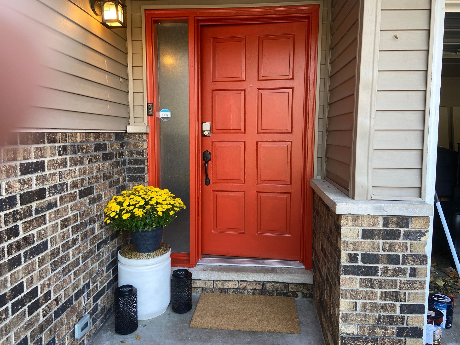 A red front door with a potted plant of yellow flowers in front of it.