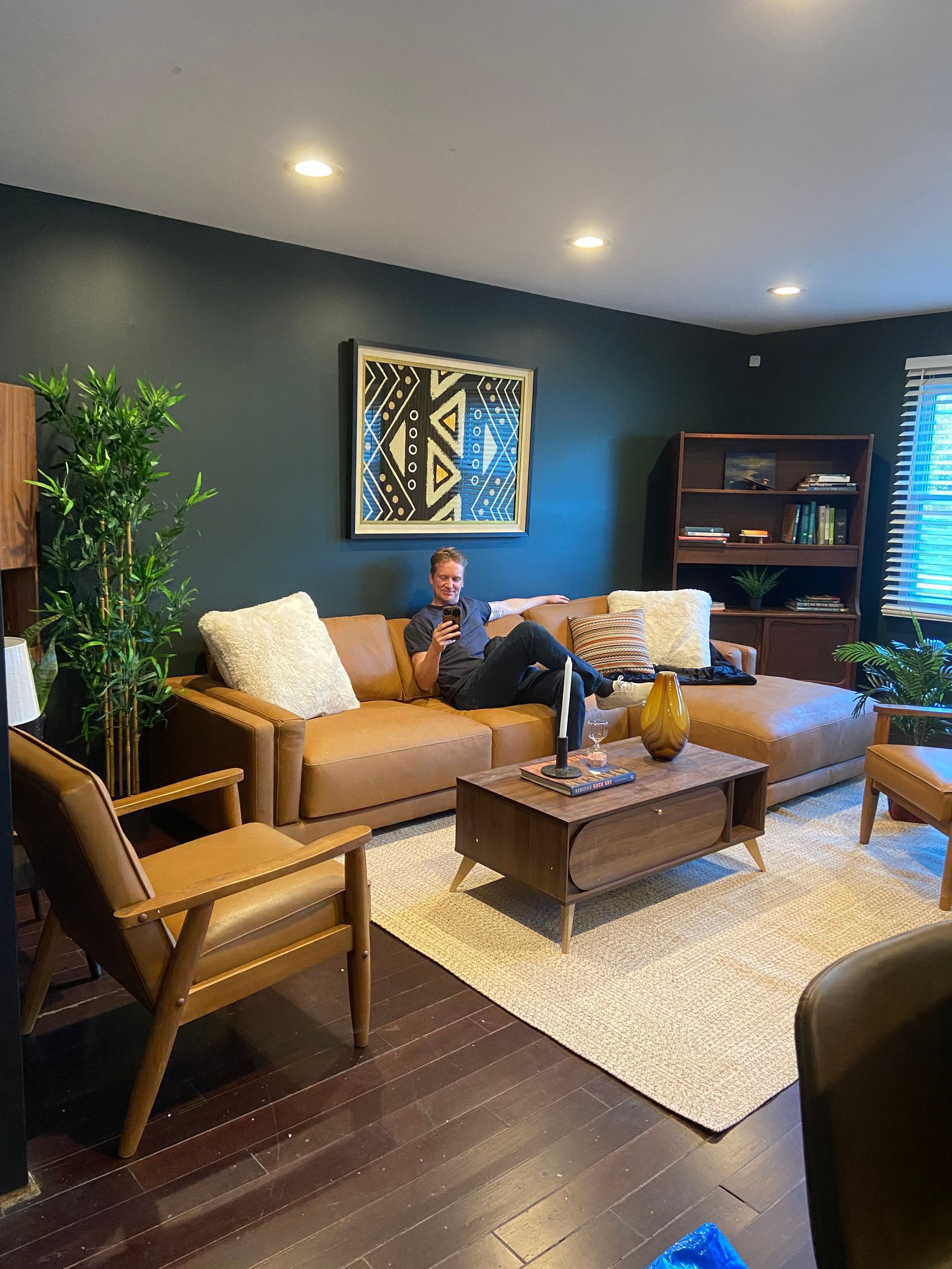 A man is sitting on a couch in a living room.