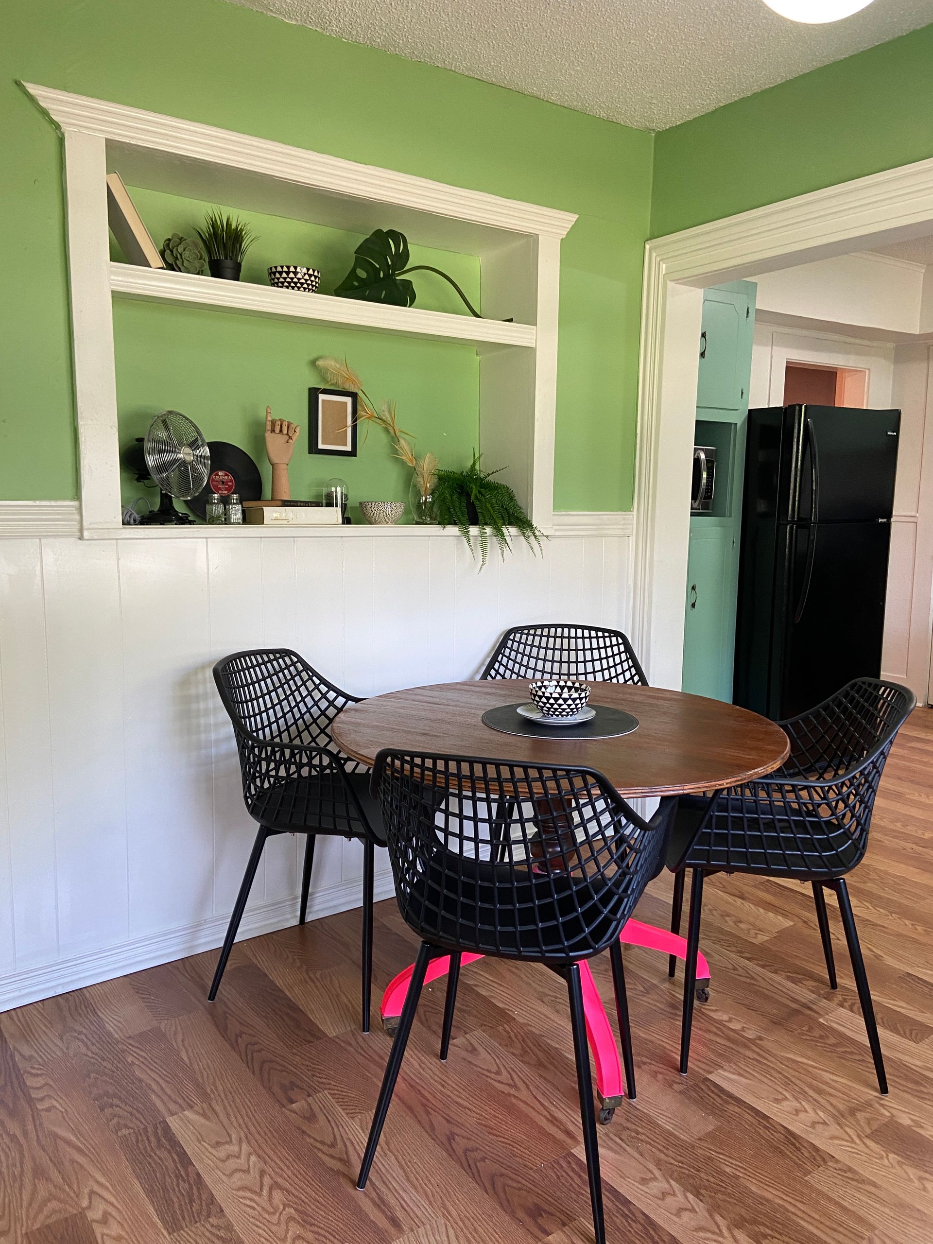 A dining room with a table and chairs and a green wall.