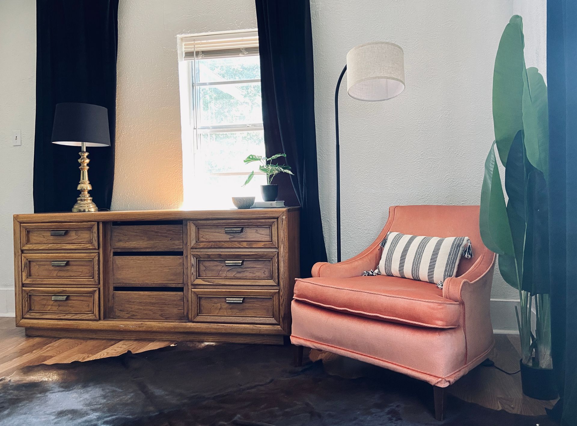 A living room with a chair a dresser and a lamp