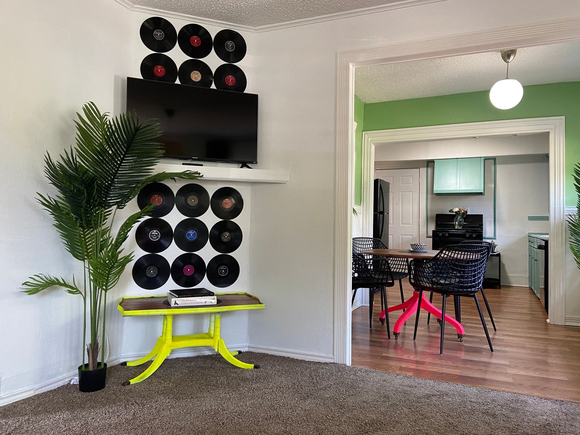 A living room with a yellow table and a television on the wall.