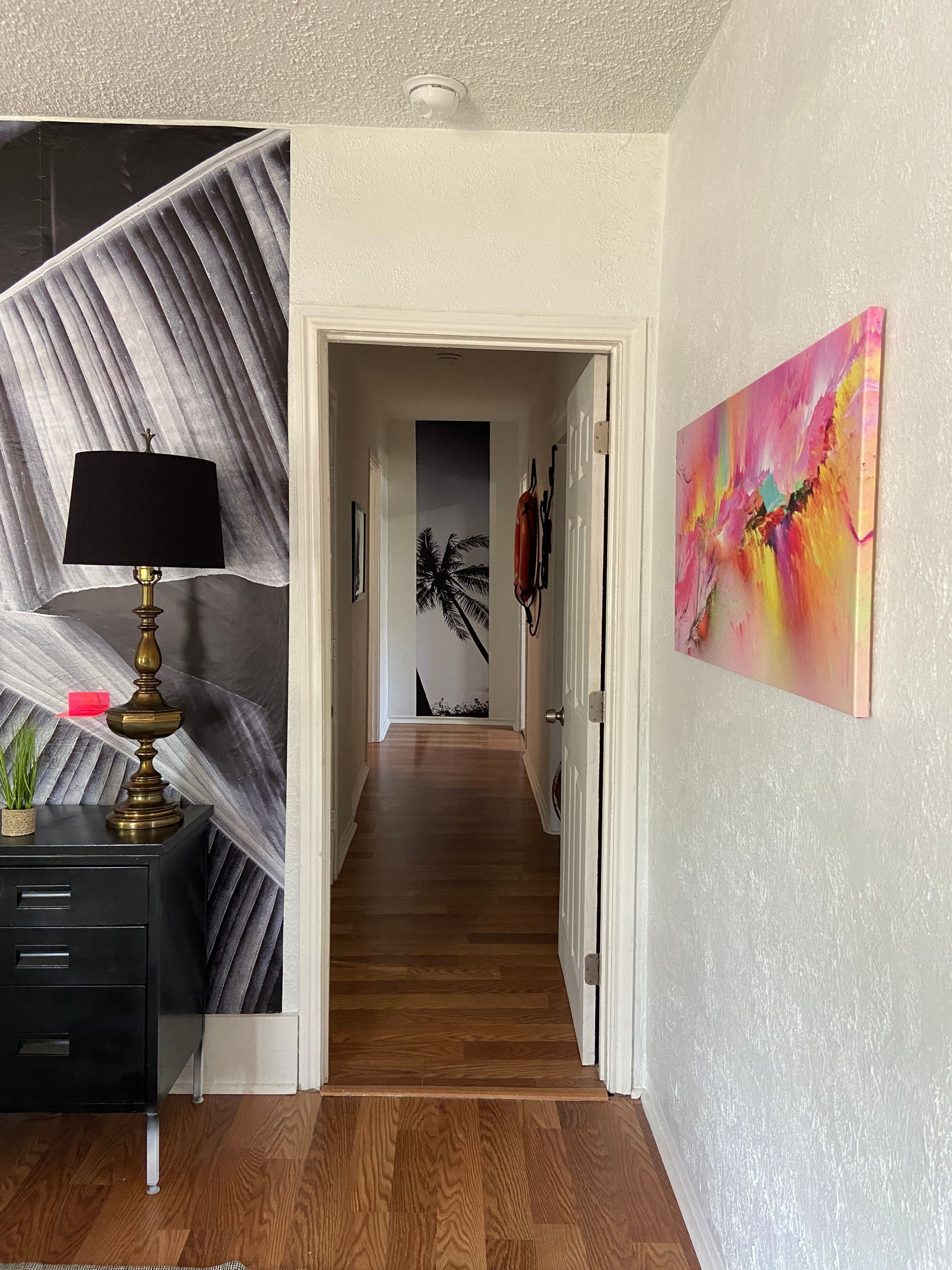 A hallway with a lamp and paintings on the wall
