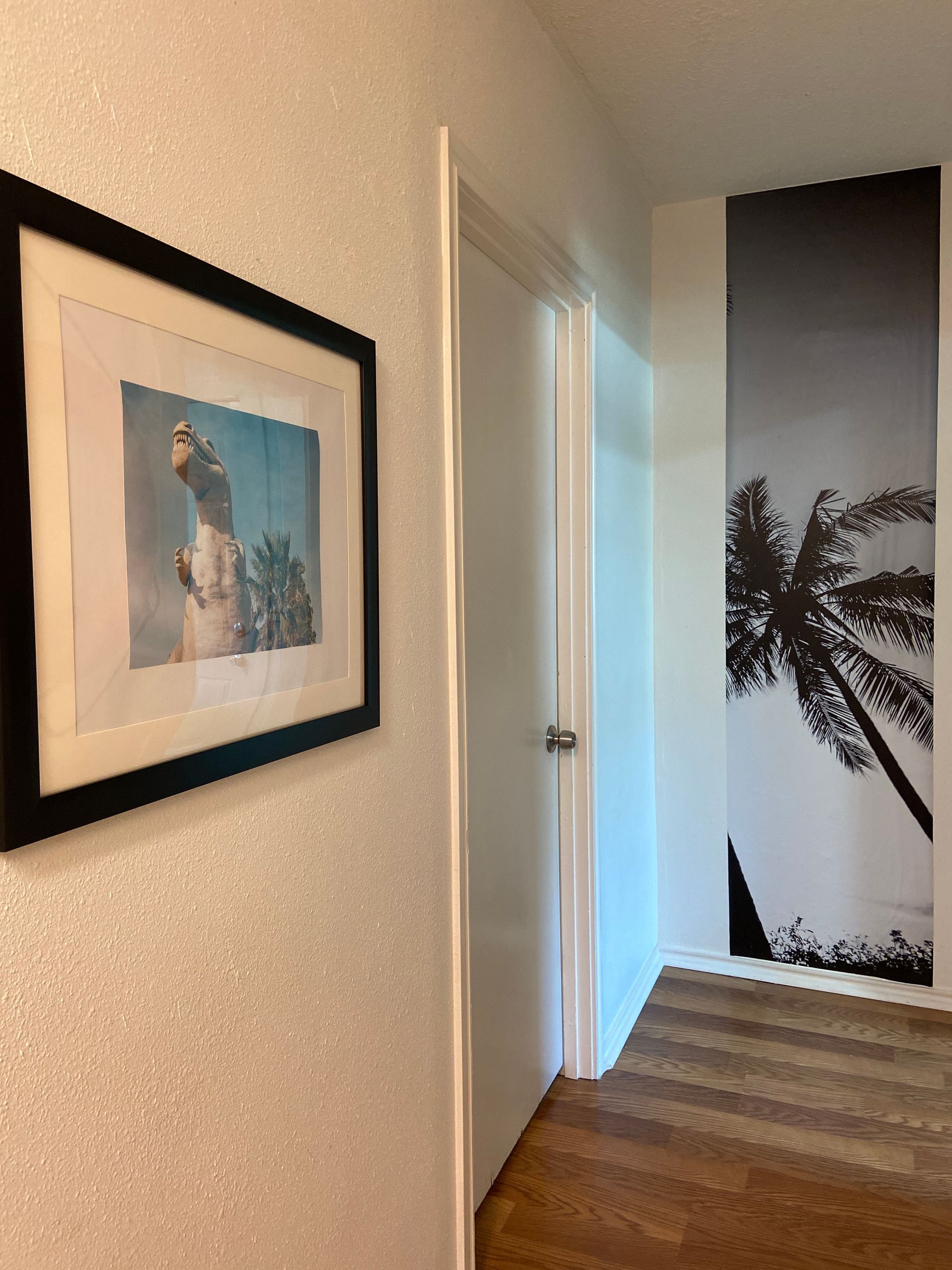 A hallway with a picture of a palm tree on the wall