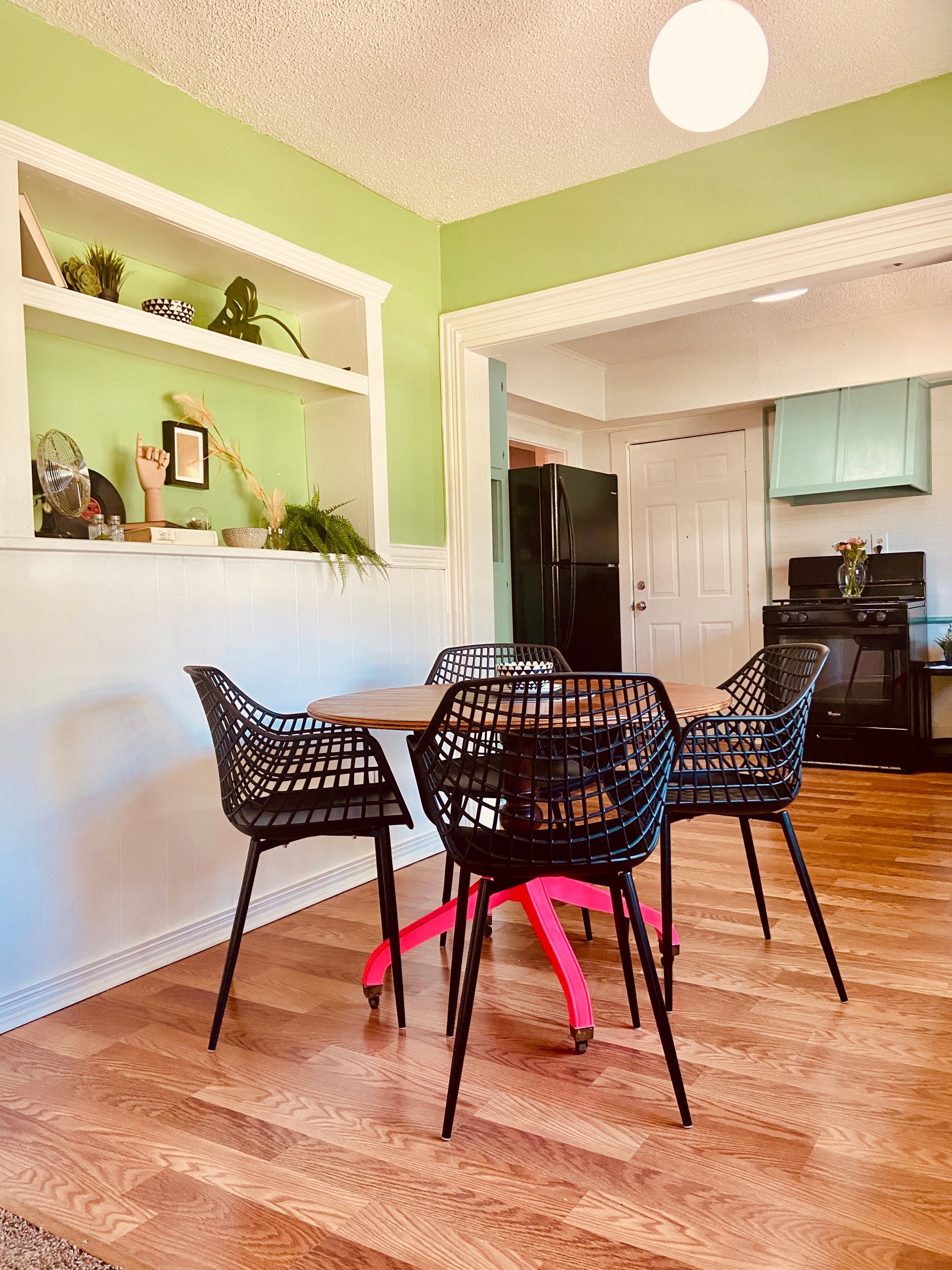 A dining room with a table and chairs and a kitchen in the background.