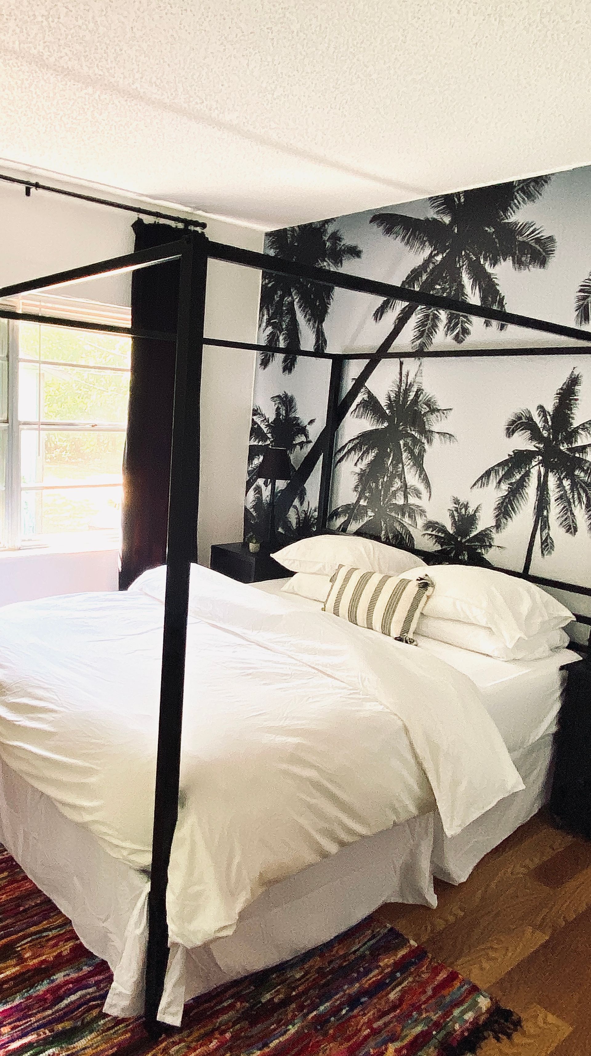 A bedroom with a canopy bed and palm trees on the wall