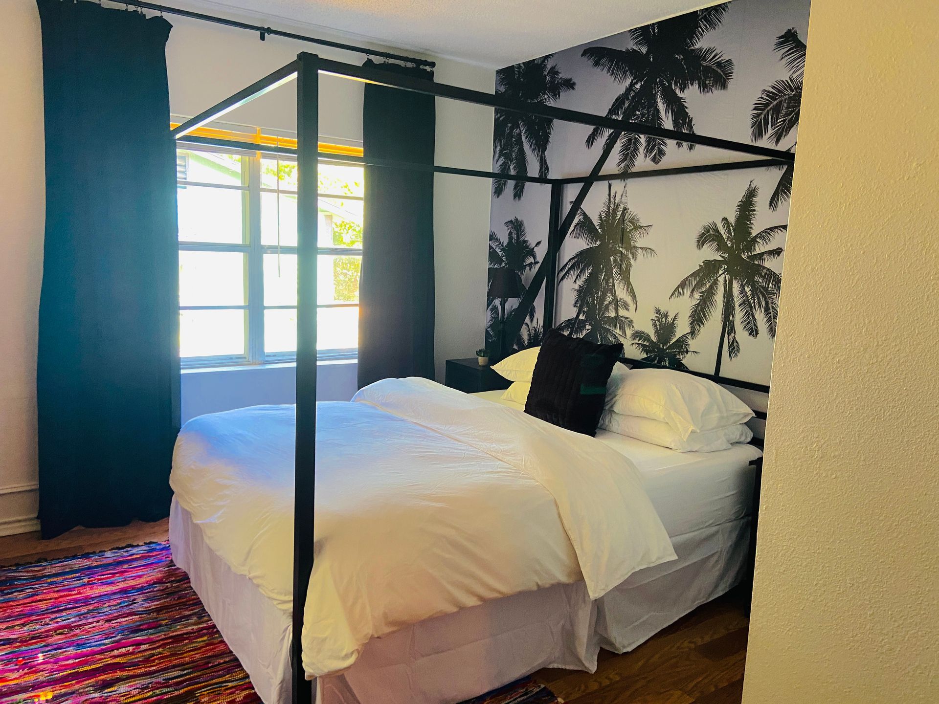 A bedroom with a four poster bed and palm trees on the wall