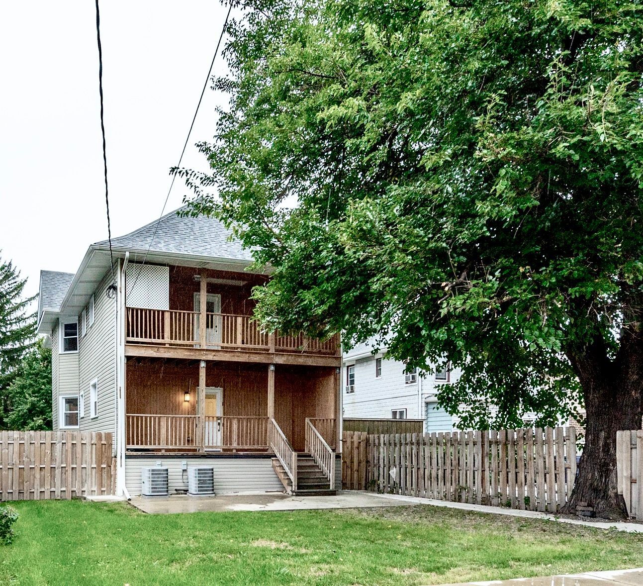 A house with a fence and a tree in front of it