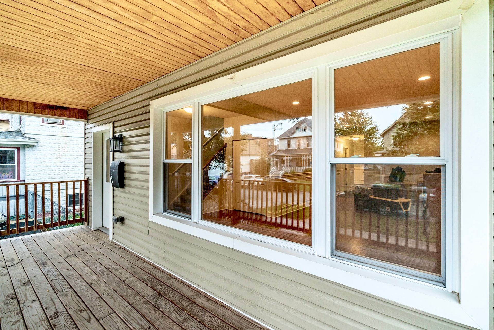 A large window on the side of a house with a wooden deck.