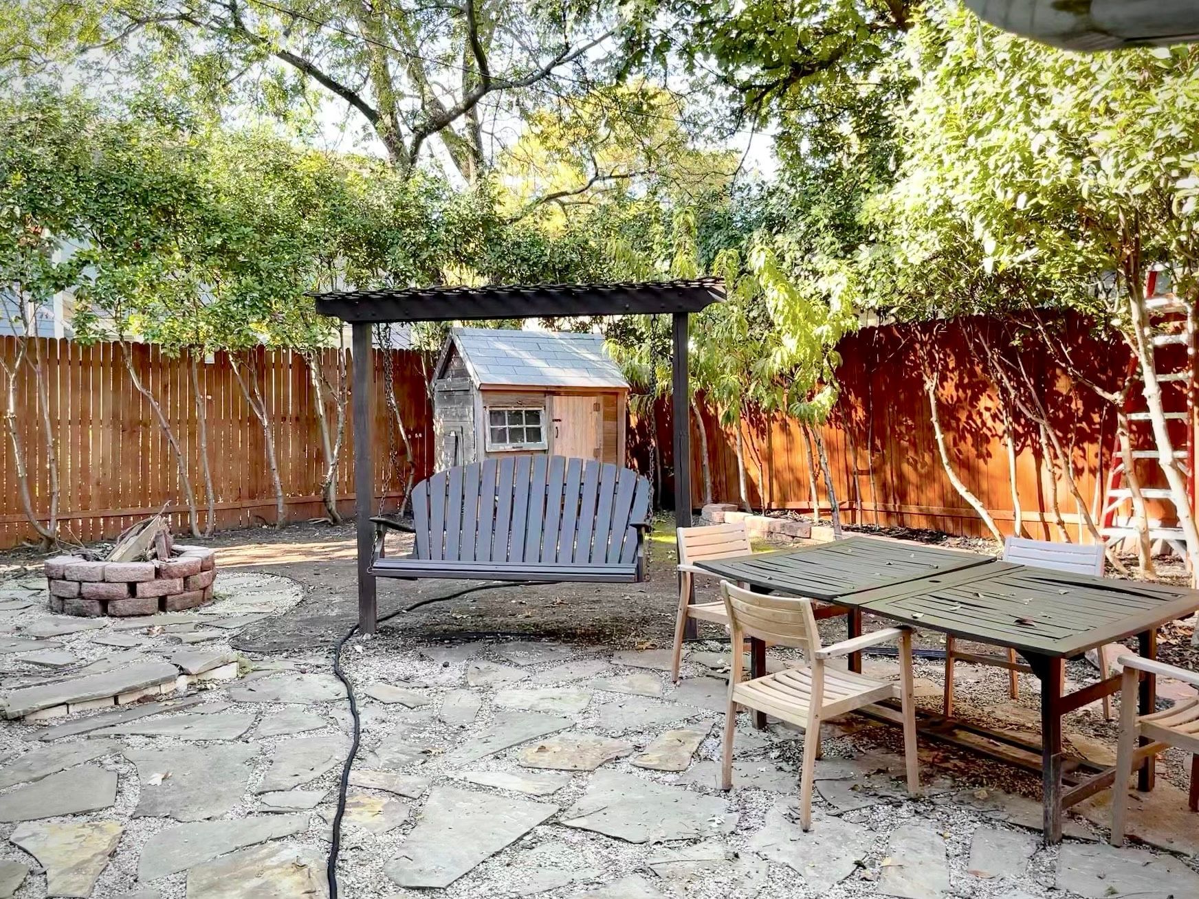 There is a table and chairs in the backyard with a fire pit.