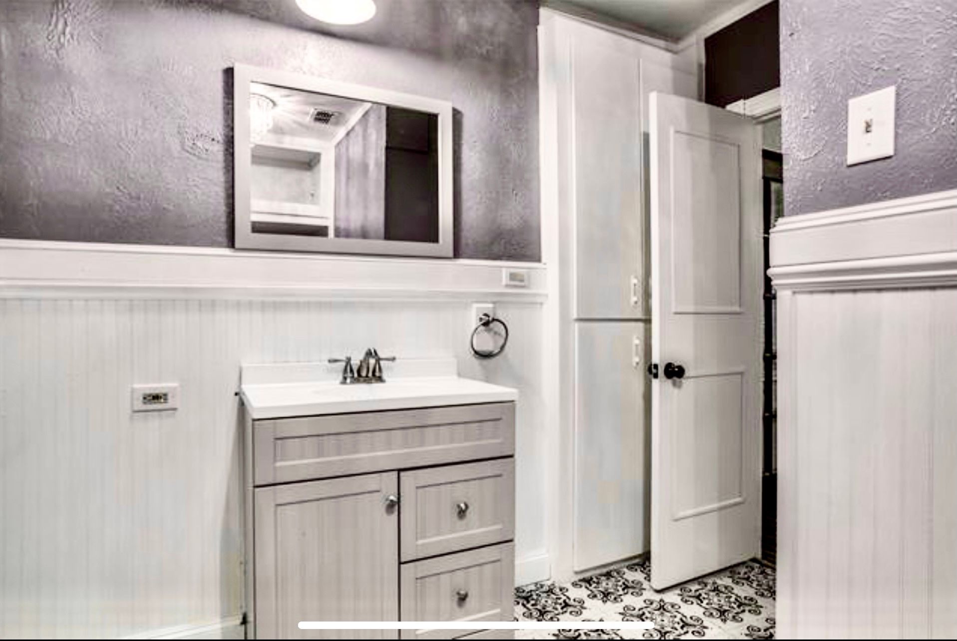 A bathroom with a sink , mirror and refrigerator.