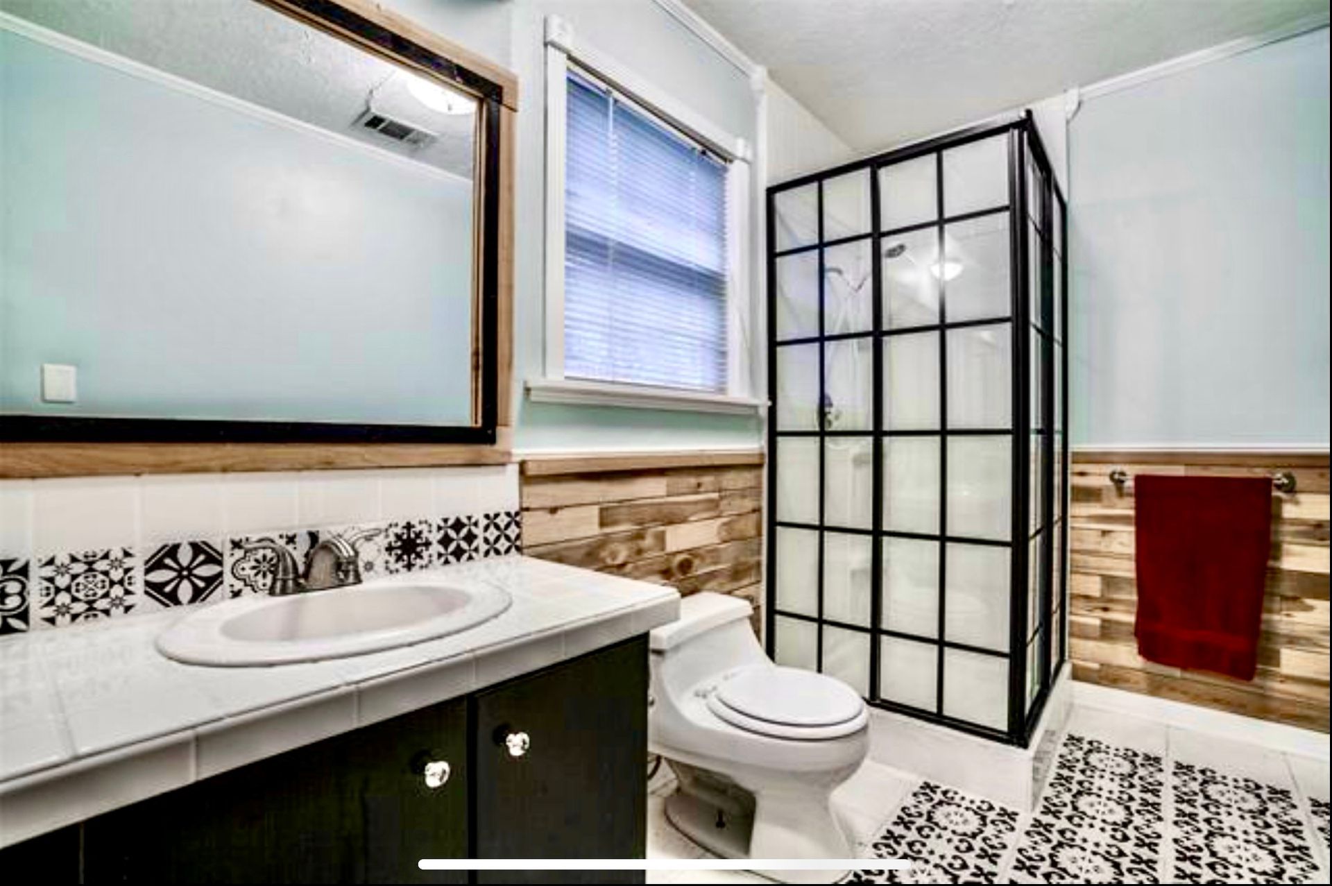 A bathroom with a toilet , sink , mirror and walk in shower.