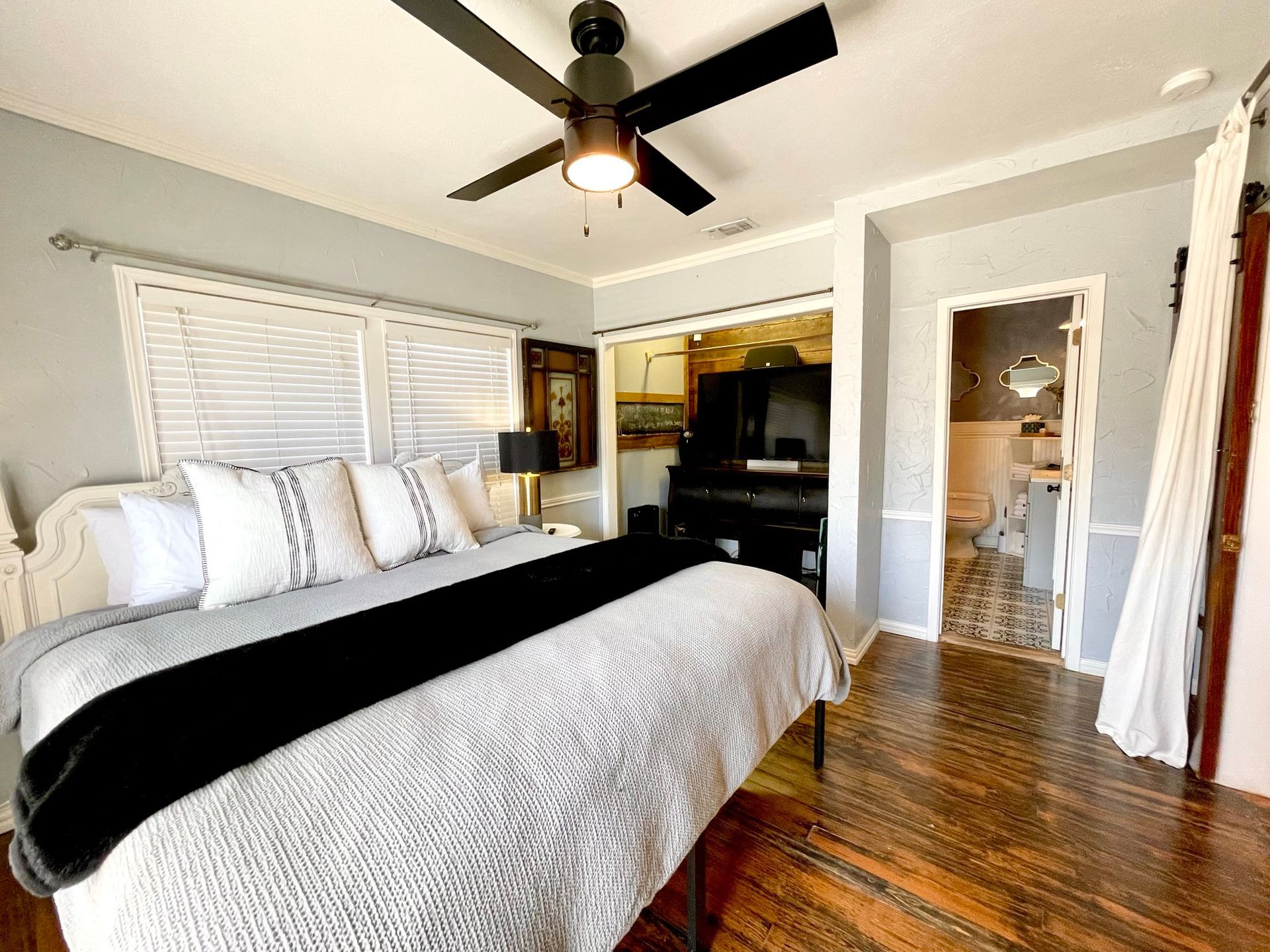 A bedroom with a king size bed and a ceiling fan.