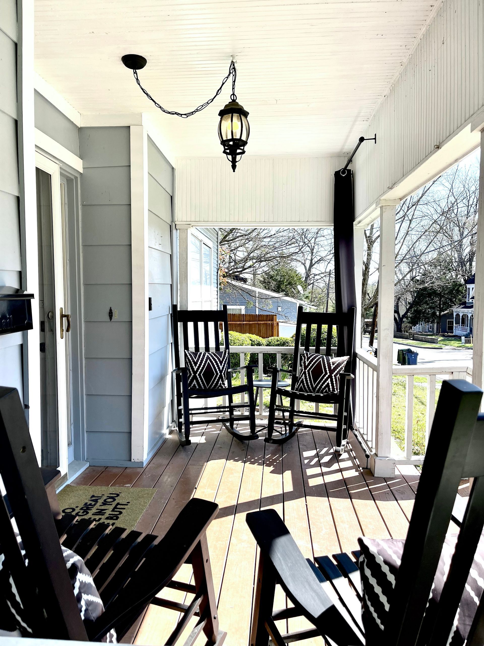 There are two rocking chairs on the porch of a house.