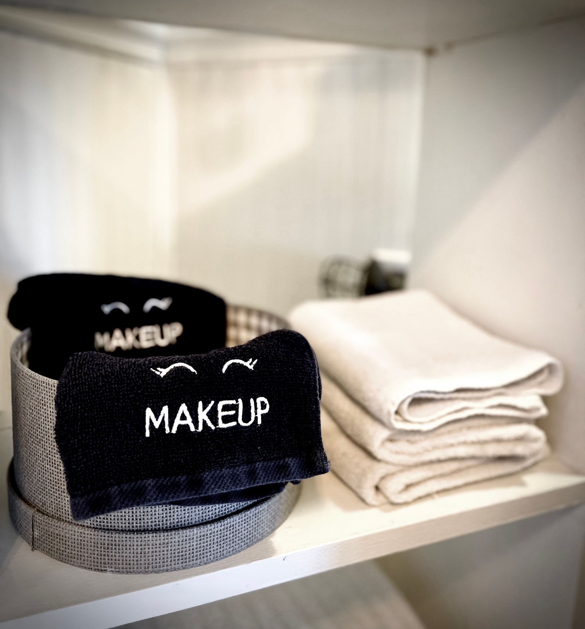 A shelf with towels and a bag that says makeup on it