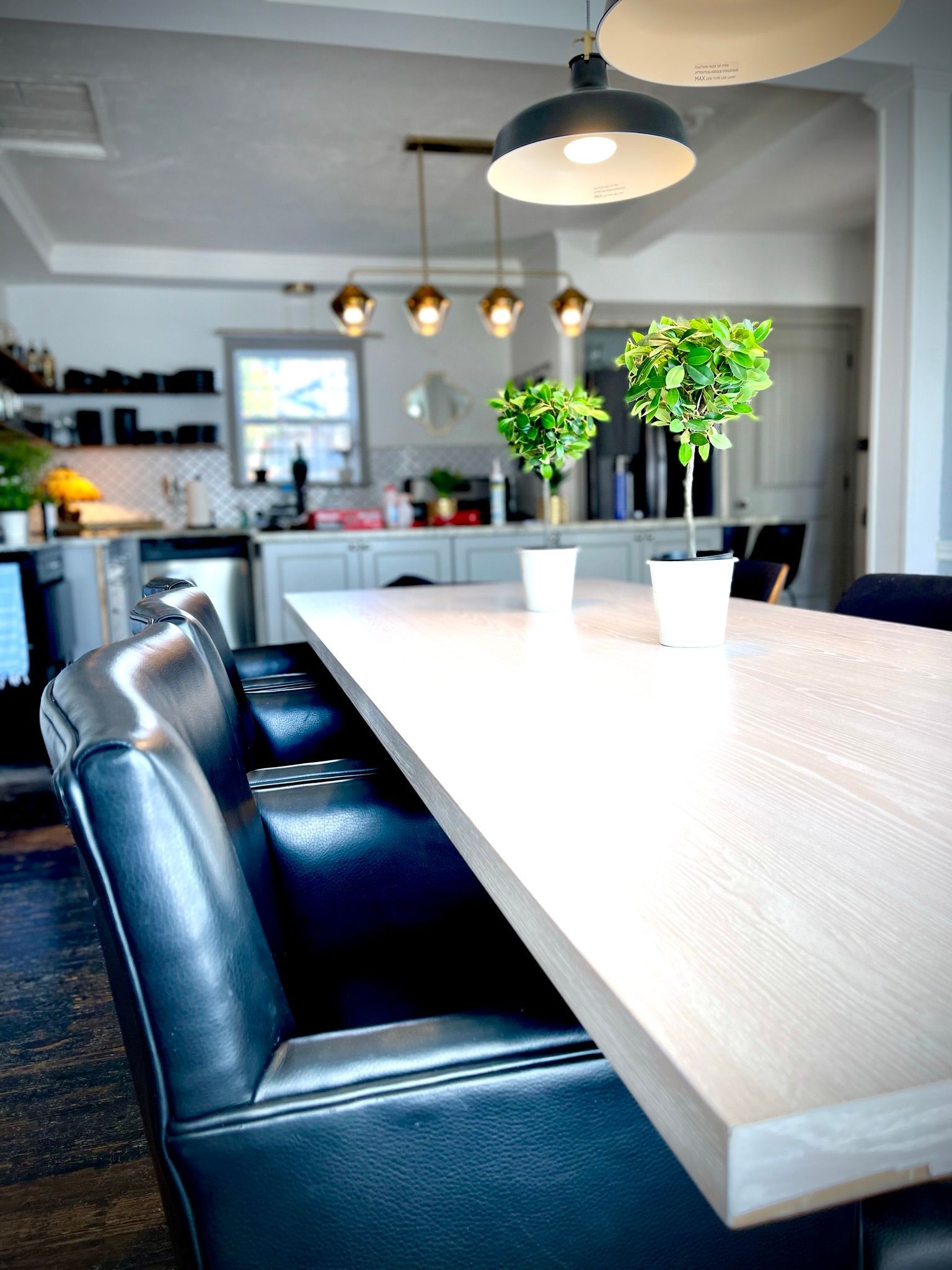 A kitchen with a table and chairs and potted plants on it.
