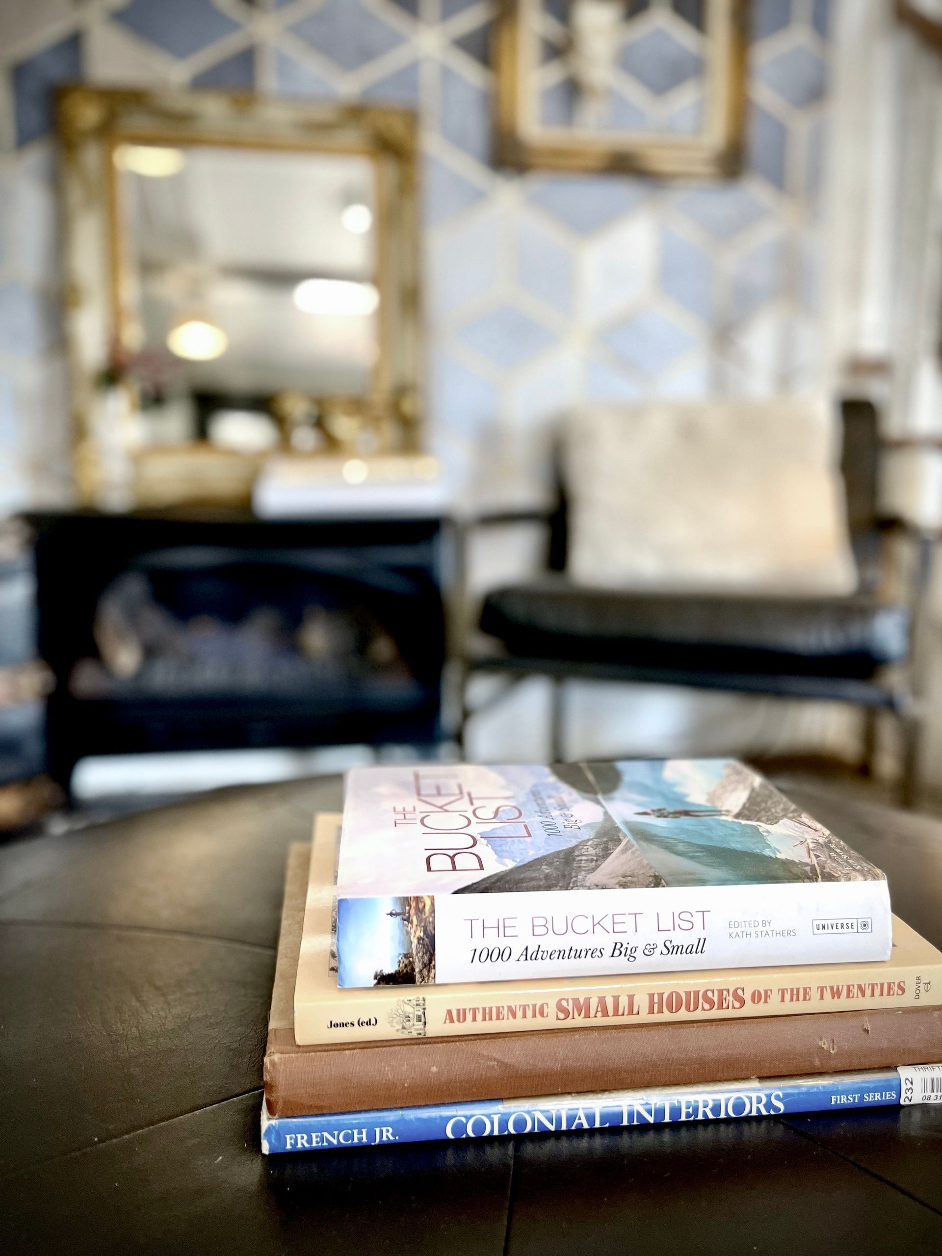 A stack of books is sitting on a coffee table in a living room.