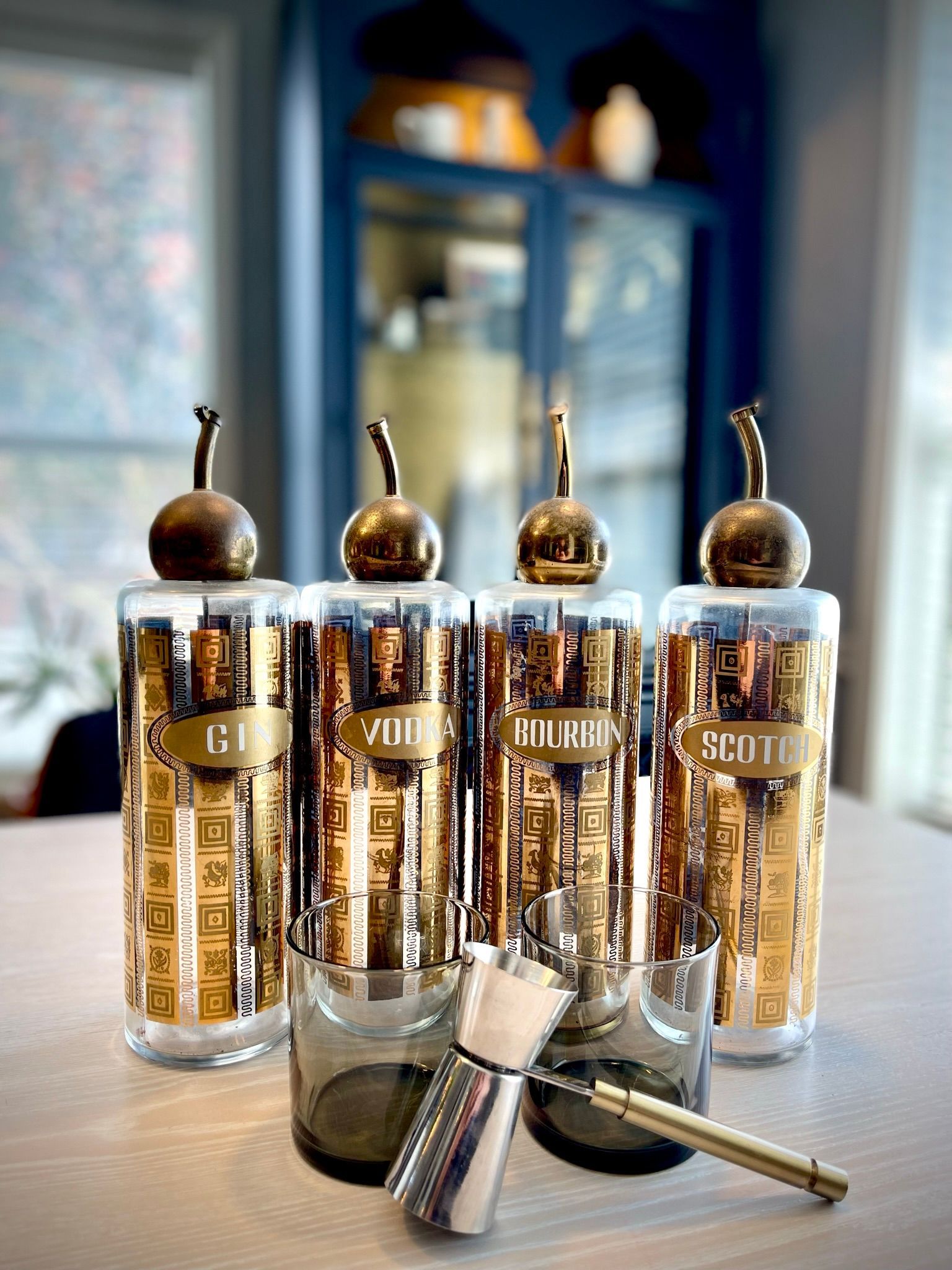 A group of glasses and a shaker are sitting on a table.