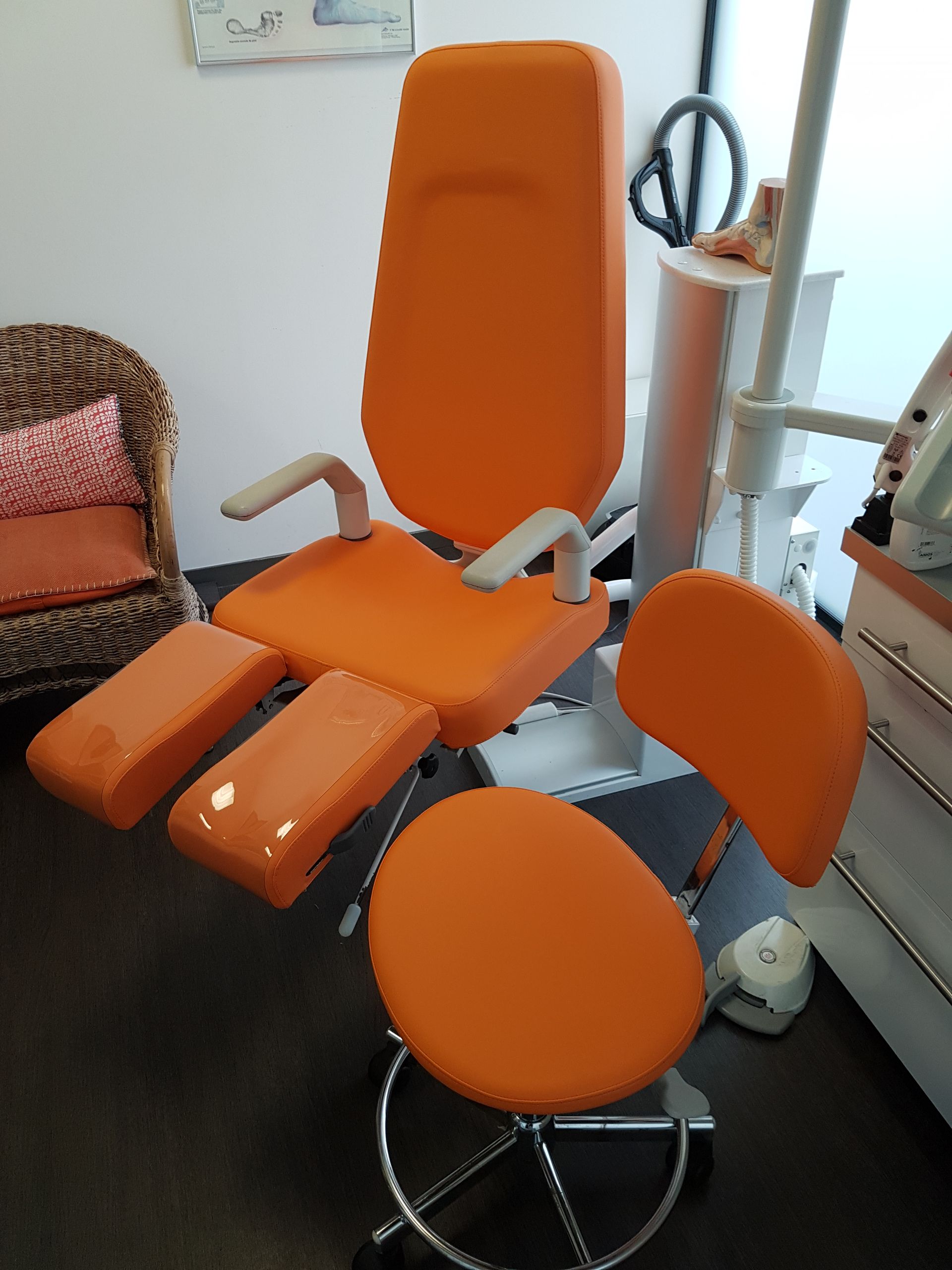 Chaise dentaire orange et tabouret d'assistant dans un bureau.