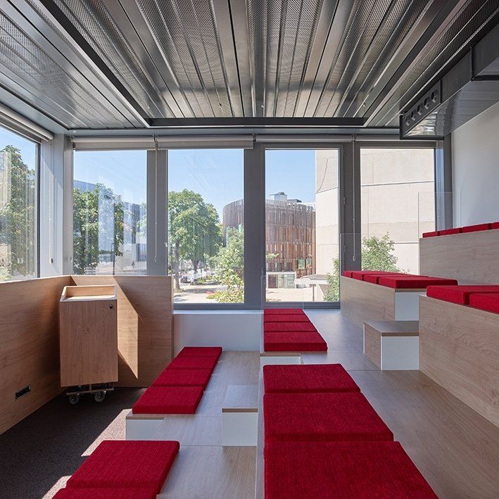 Intérieur avec coussins rouges sur des sièges à gradins près des fenêtres, avec une vue extérieure.