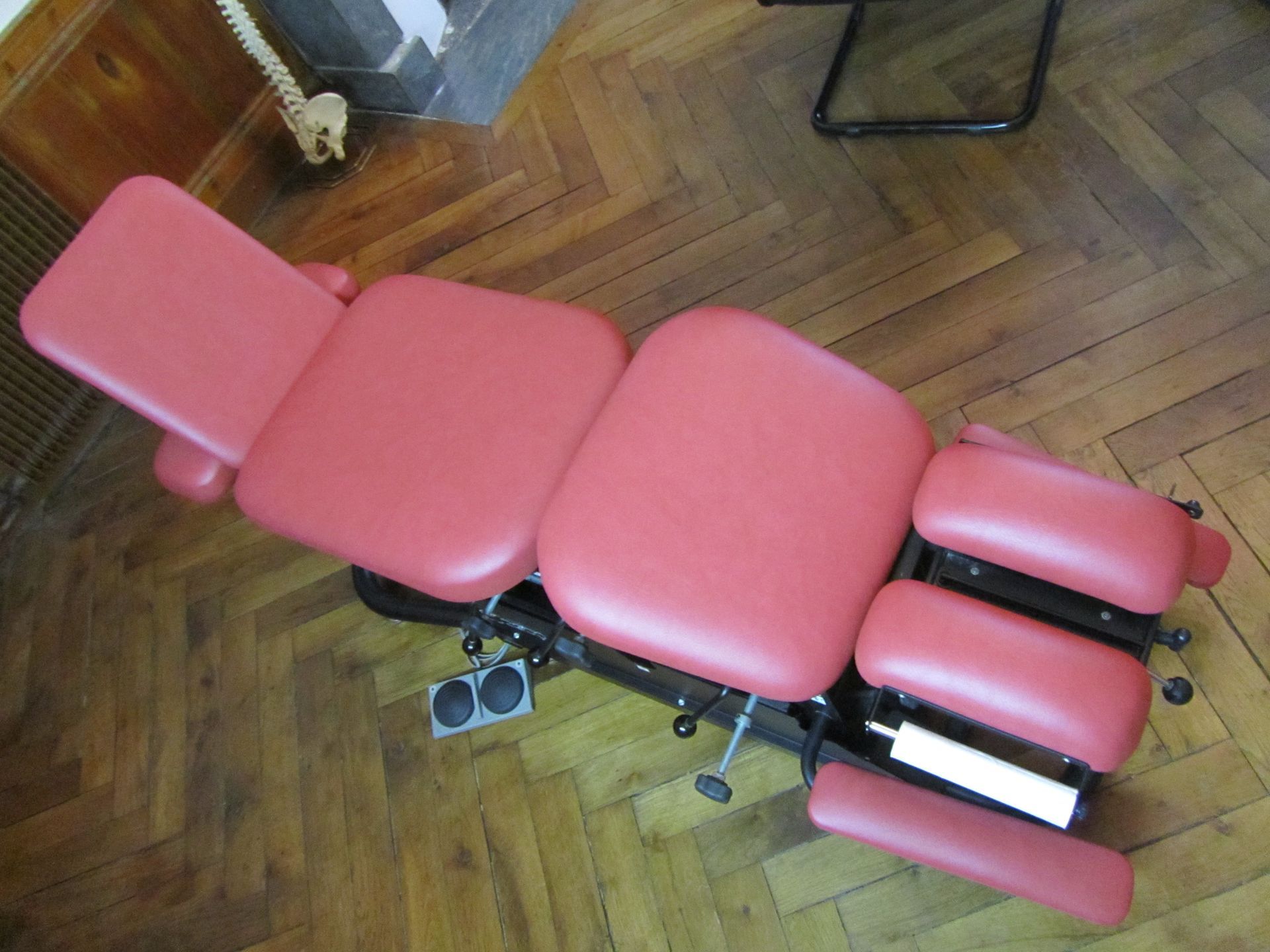 Table chiropratique rouge sur plancher en bois.
