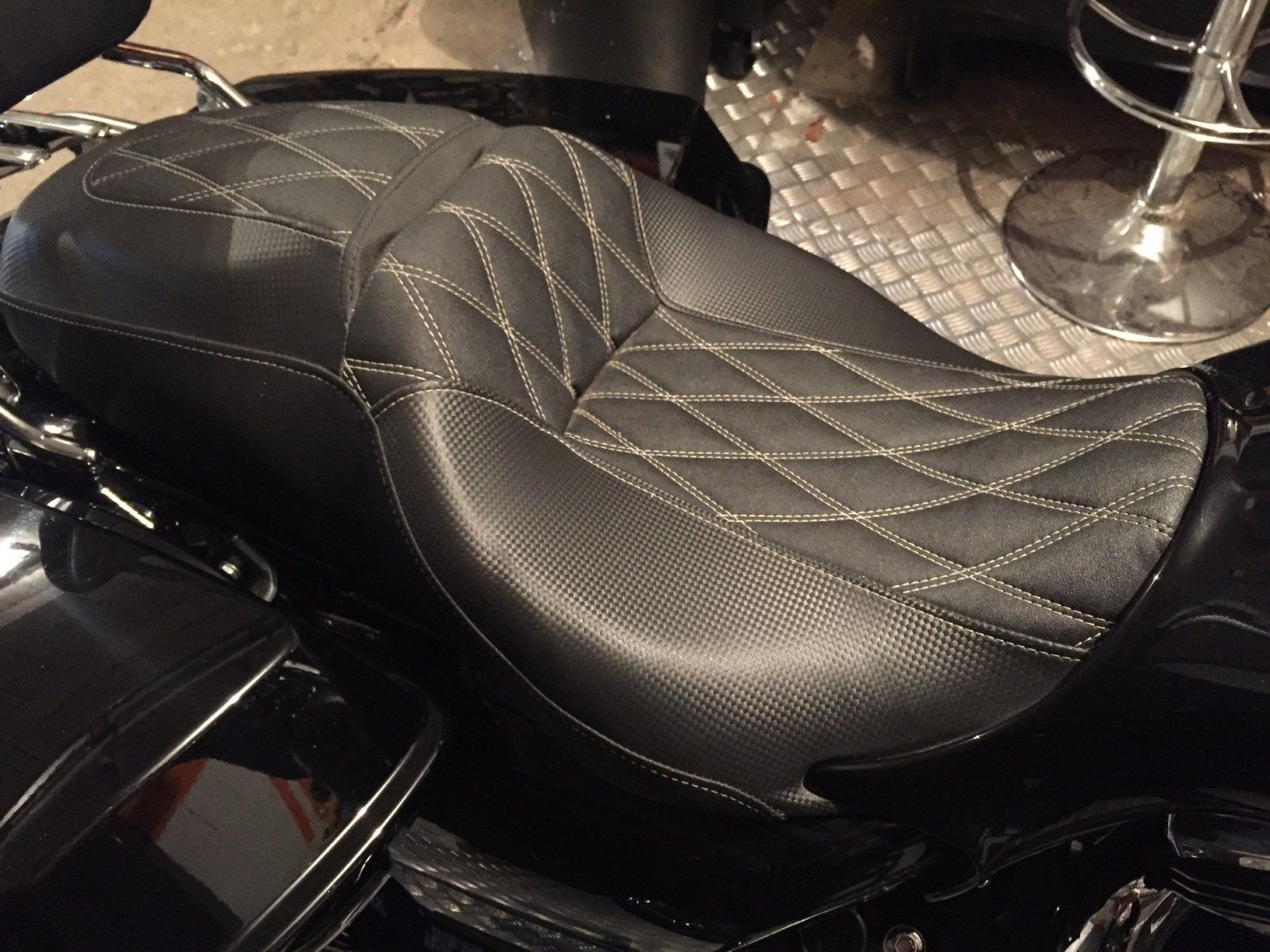 Selle de moto noire avec surpiqûres en losange, fil clair, sur une moto.