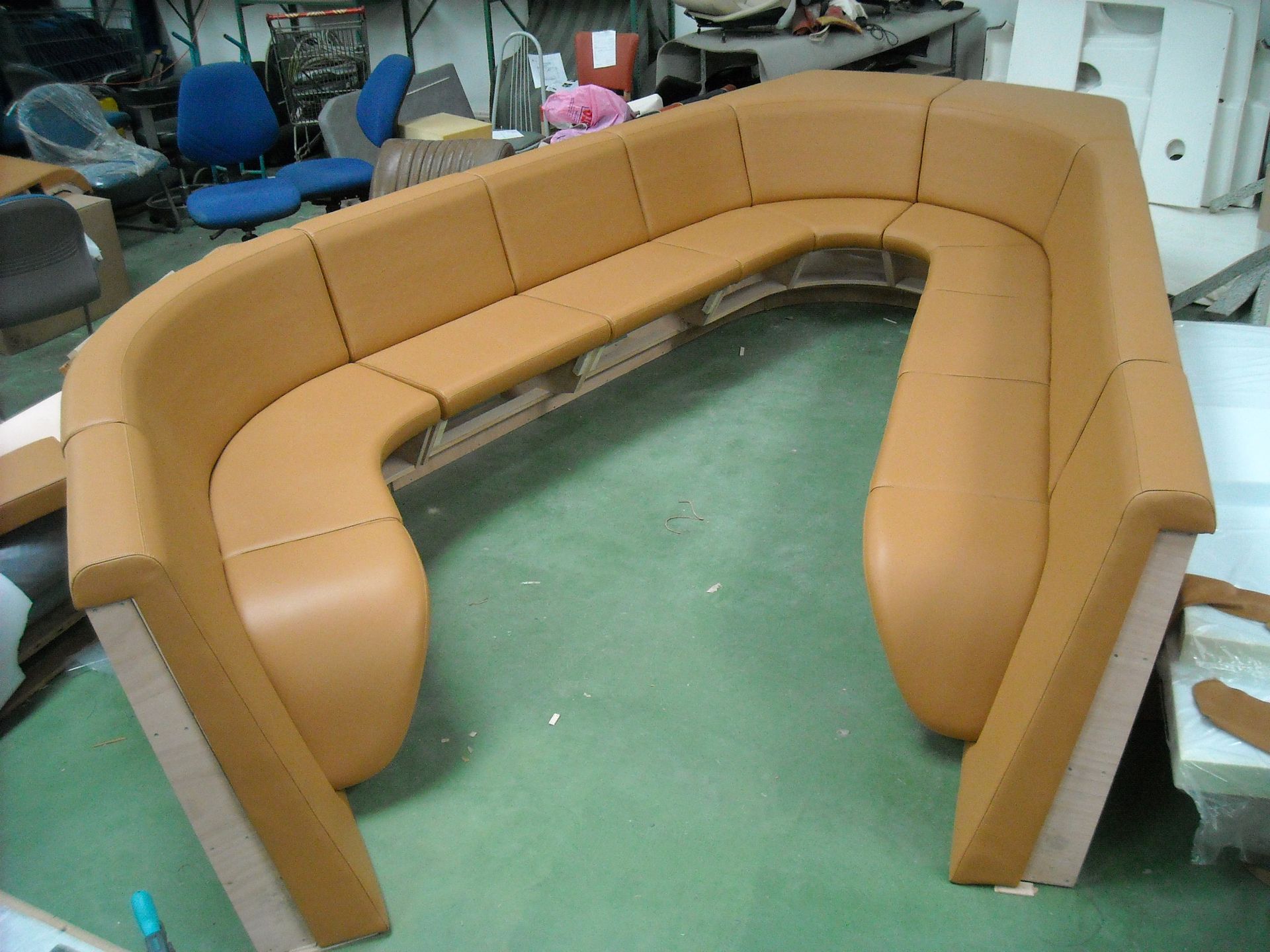Canapé en U en cuir beige dans un atelier, structure en bois, prêt à être installé.