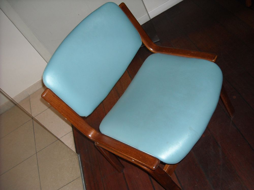 Chaise rembourrée bleue avec cadre en bois, posée sur un plancher en bois foncé.