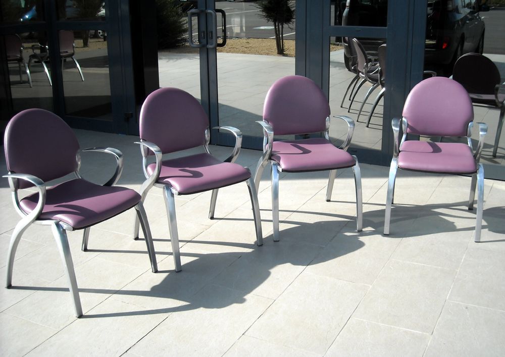 Quatre chaises violettes avec des cadres argentés à l'extérieur d'un bâtiment.