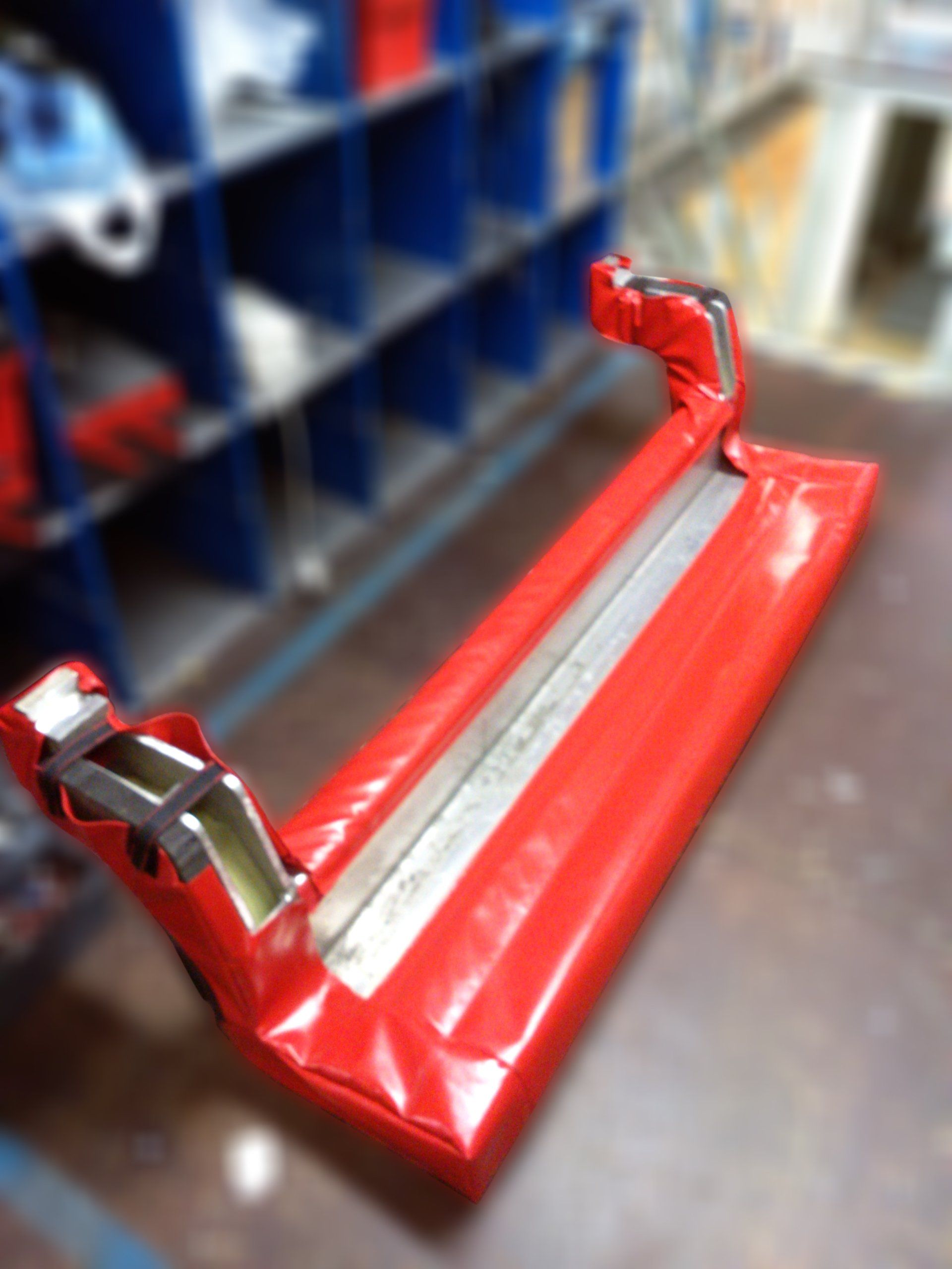 Dispositif de sécurité rembourré rouge avec supports métalliques, éventuellement à usage industriel.