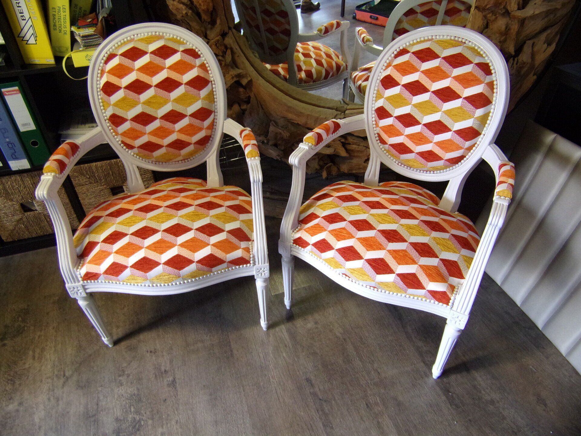 Deux fauteuils blancs avec un revêtement à motifs losanges orange et jaune.