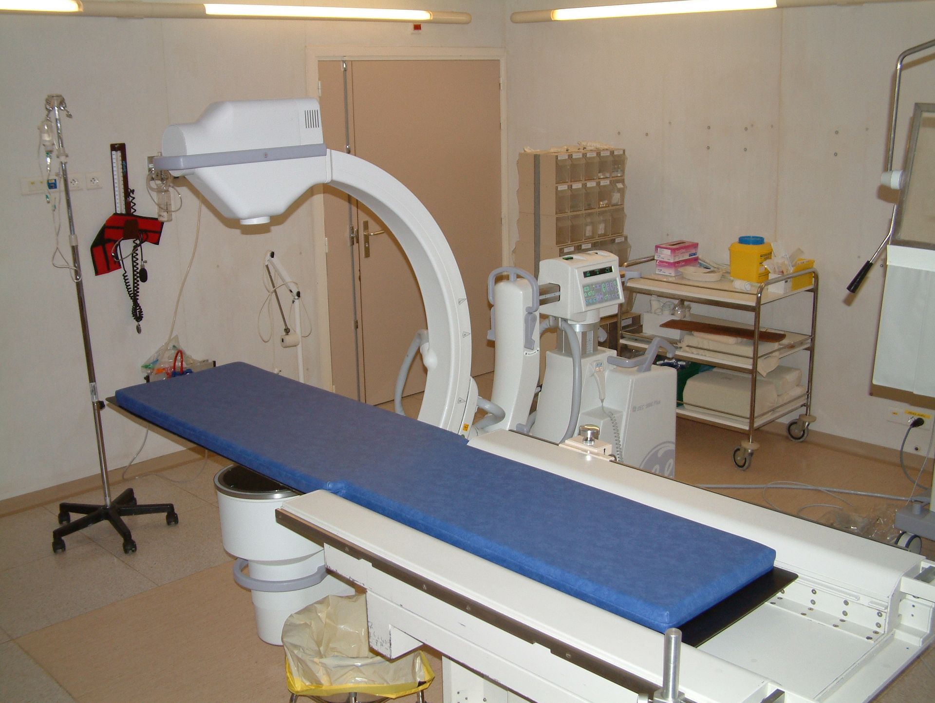 Appareil de radiographie médicale avec un arceau au-dessus d'une table dans une salle clinique.