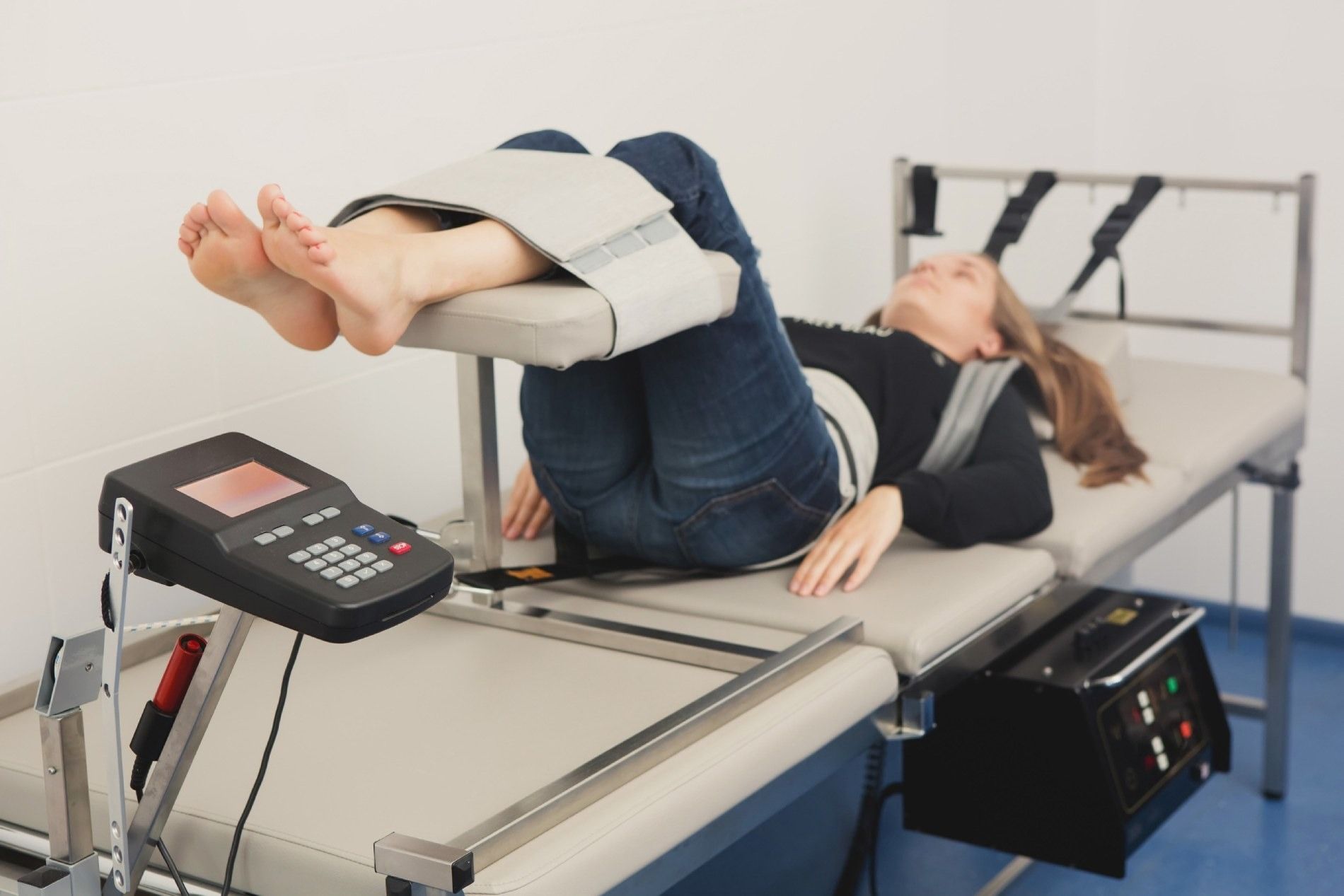 Una mujer está acostada en una cama con las piernas levantadas y un dispositivo en la espalda.