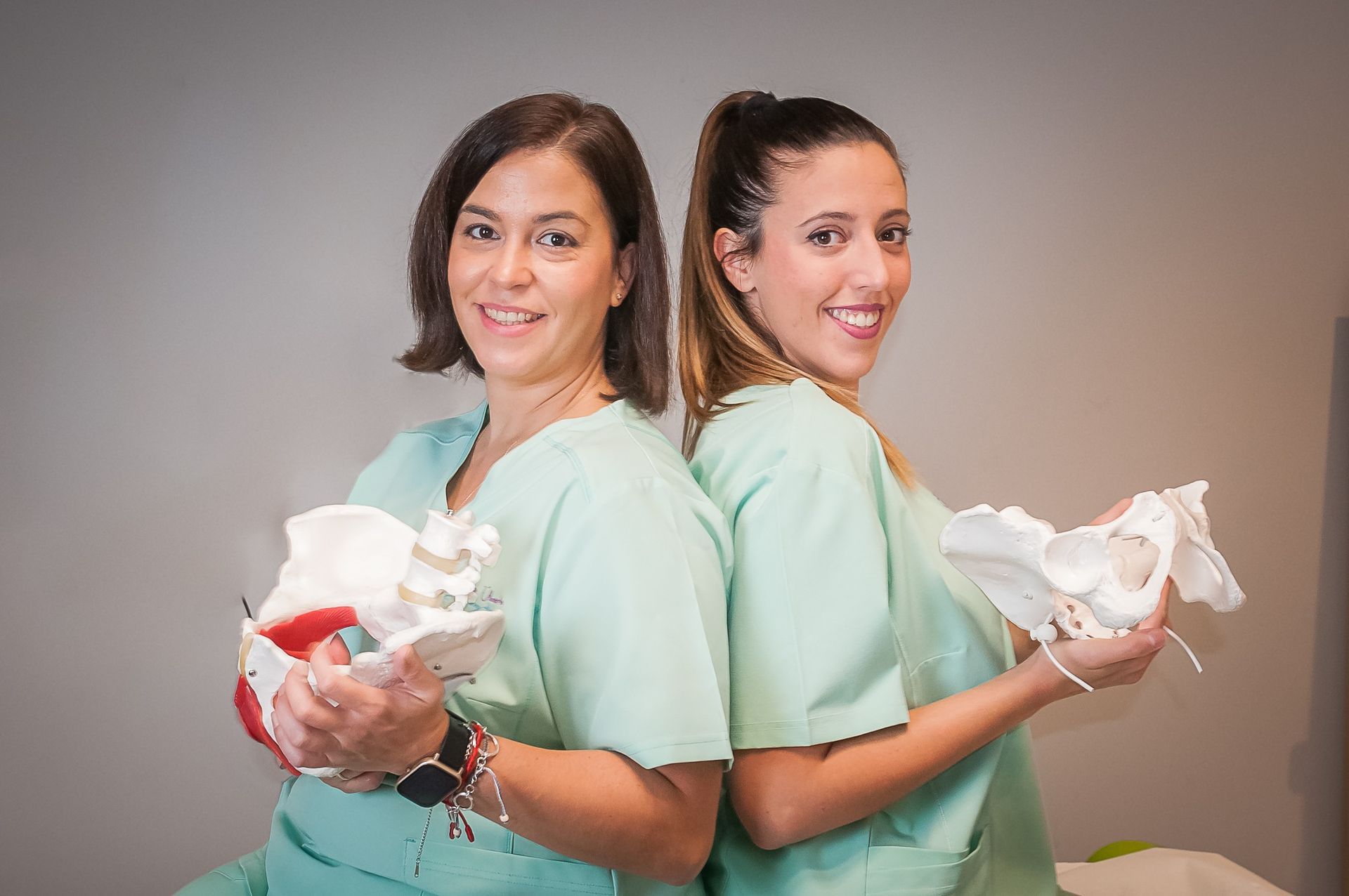 Dos mujeres están paradas espalda con espalda sosteniendo esqueletos.