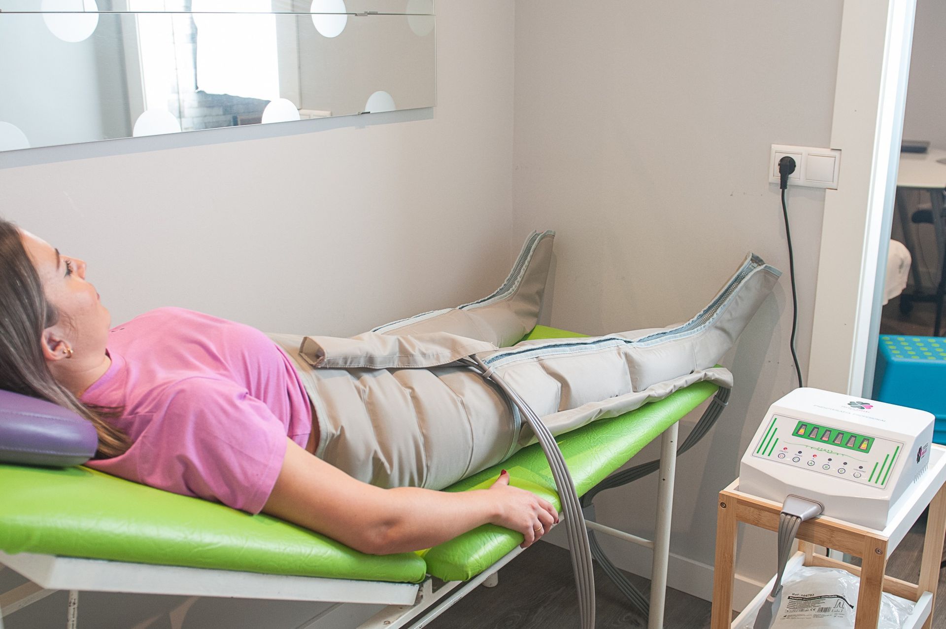 Una mujer está acostada en una cama verde recibiendo un masaje en las piernas.