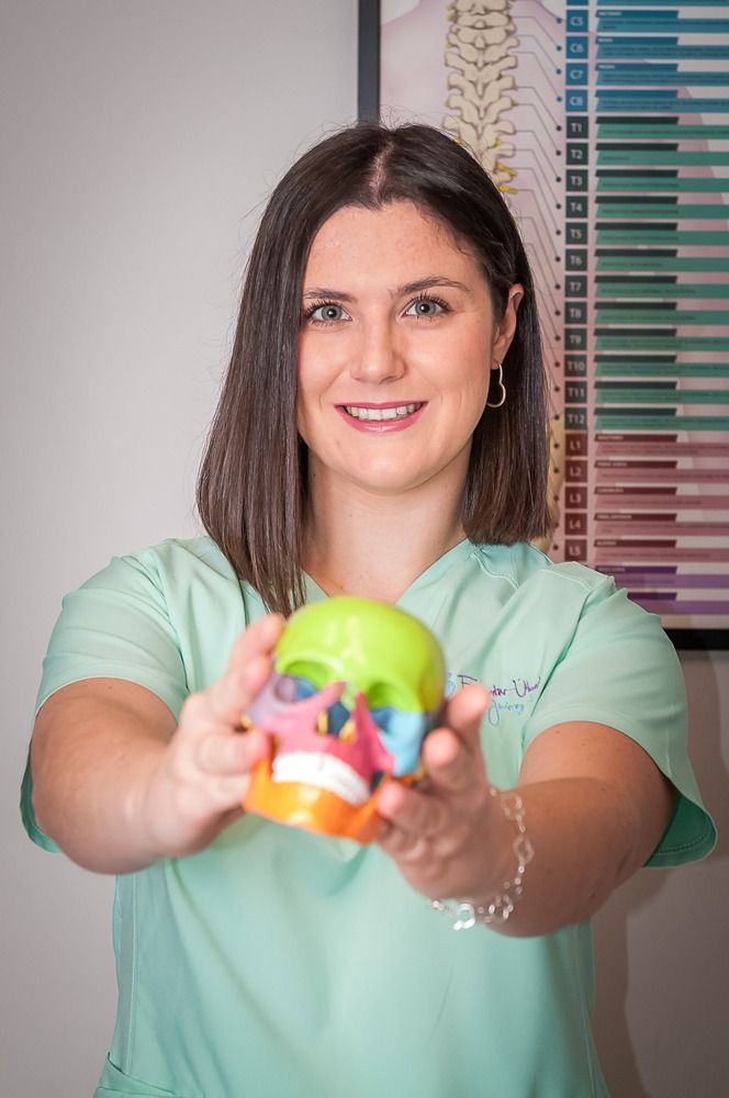 Una mujer sostiene un modelo de una calavera en sus manos.
