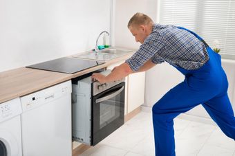 Un hombre está instalando un horno en una cocina.