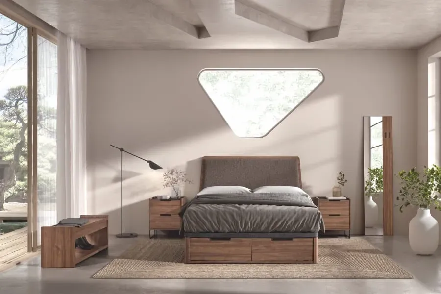 Dormitorio moderno con cama tapizada en gris, colchón blanco, almohadas negras y una manta oscura.