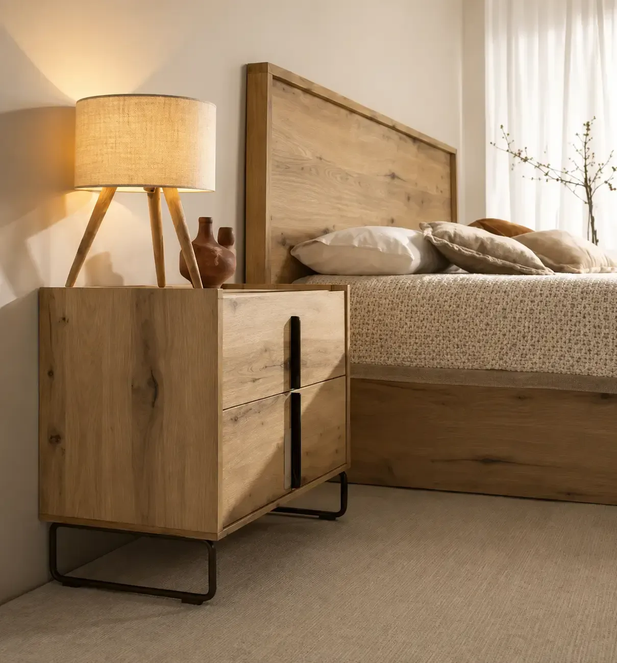 Acogedor rincón de dormitorio con cama de madera, mesita de noche a juego y lámpara encendida junto a la ventana.