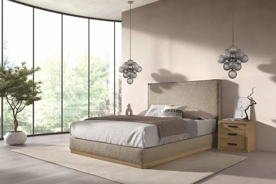 Dormitorio moderno con cama tapizada en gris, colchón blanco, almohadas negras y una manta oscura.