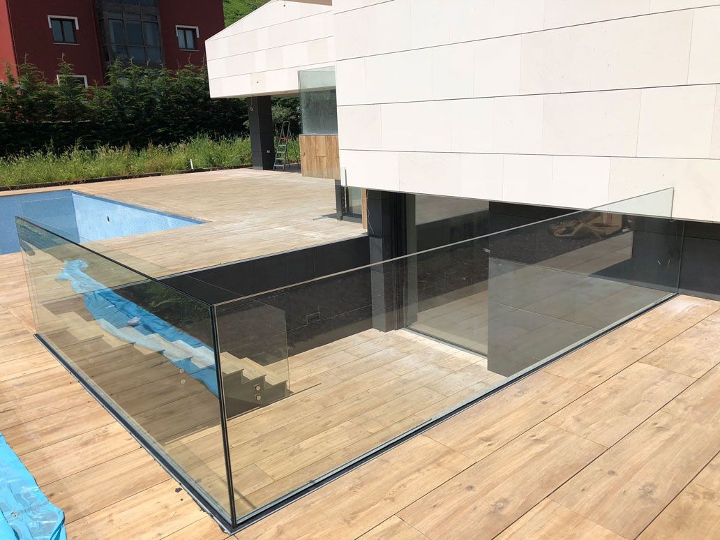 Una piscina con una barandilla de cristal que la rodea.