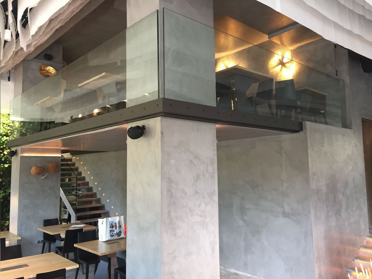 Un restaurante con mesas y sillas y barandilla de cristal.