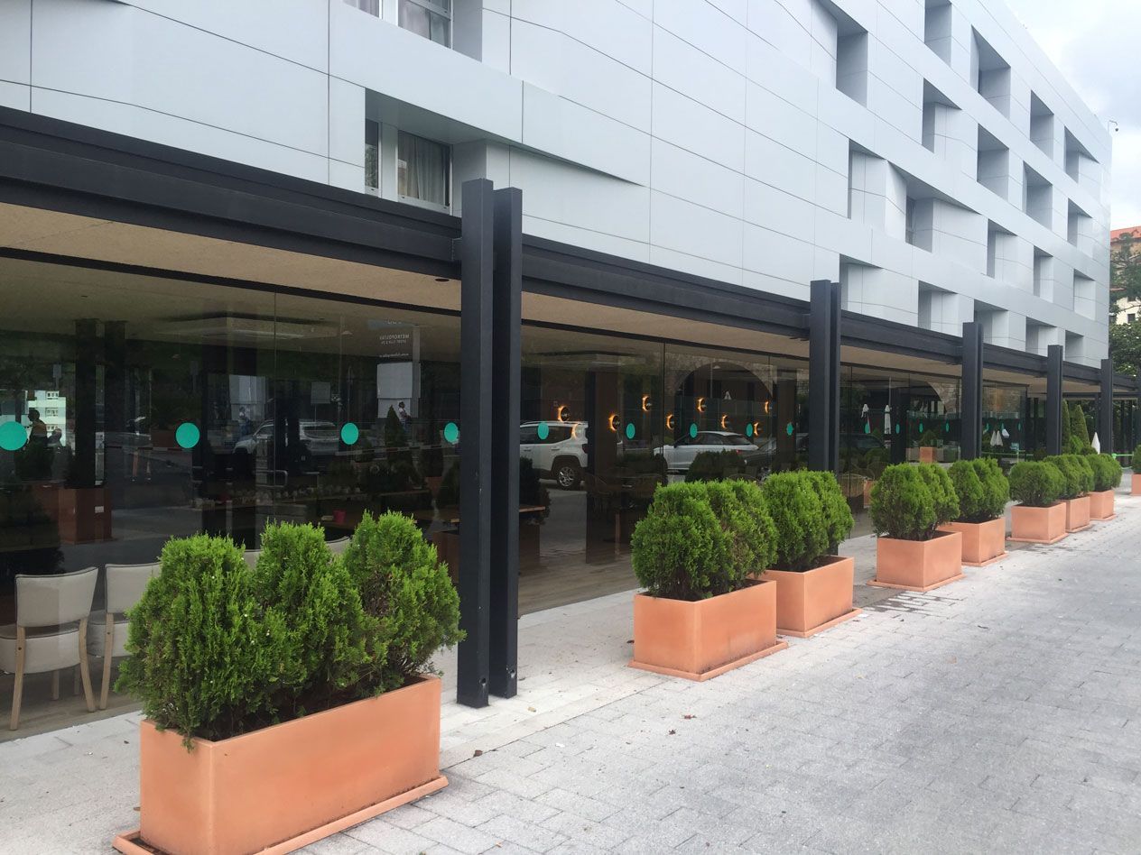 Un edificio con muchas plantas en frente.