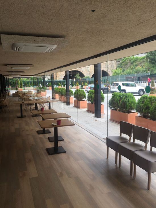 Un restaurante con mesas y sillas y muchas ventanas.