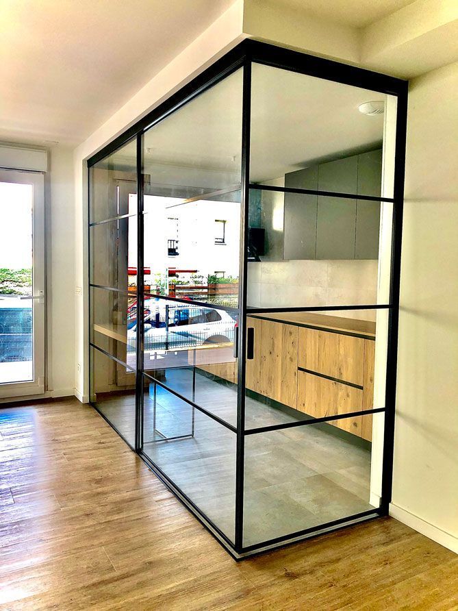 Una habitación con una puerta corrediza de vidrio entre una cocina y una sala de estar.