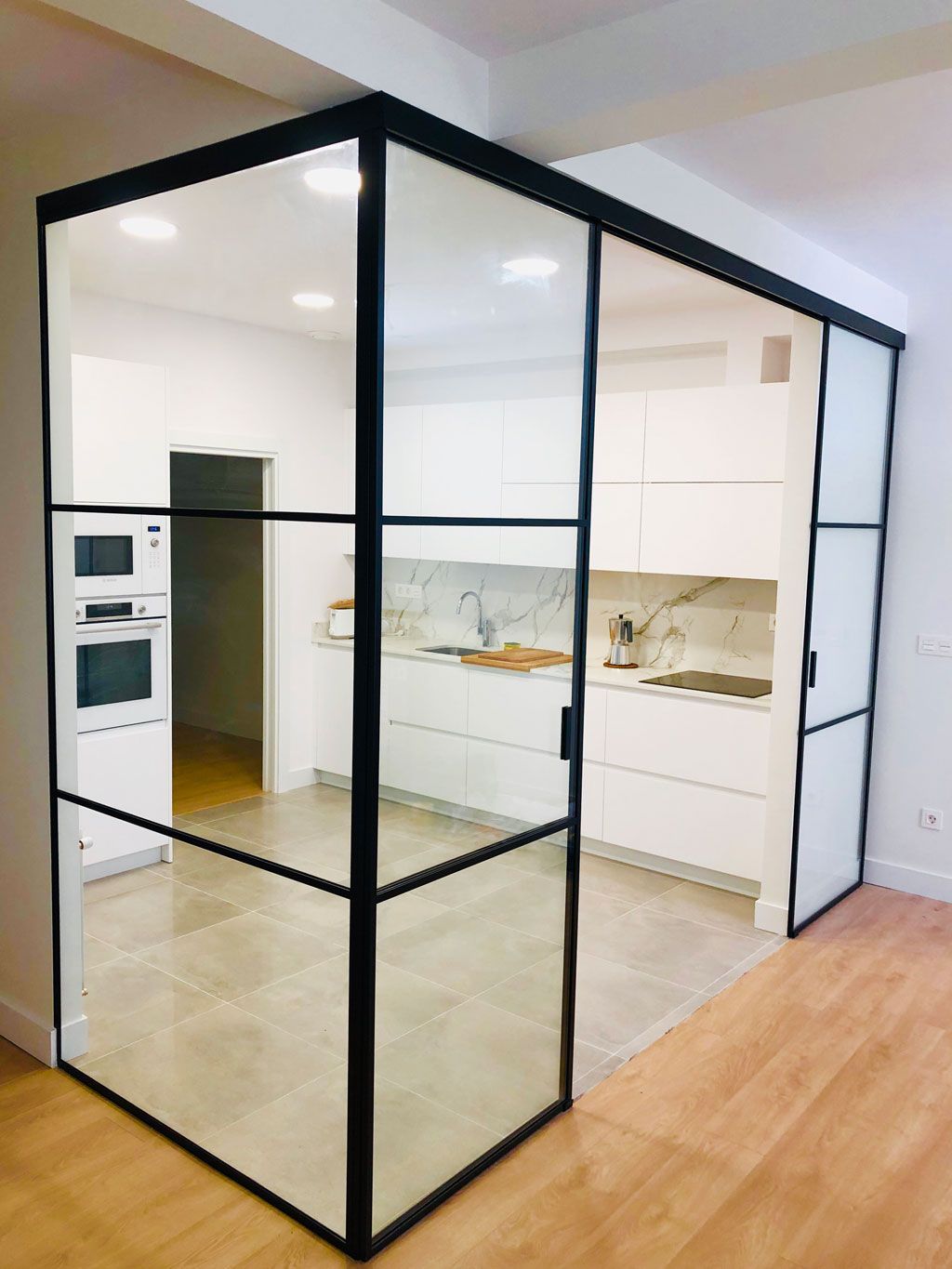 Una cocina con una puerta corrediza de vidrio entre la cocina y la sala de estar.