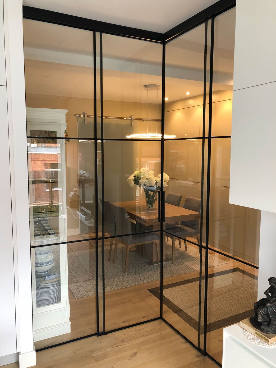 Un comedor con una mesa y sillas detrás de una pared de cristal.