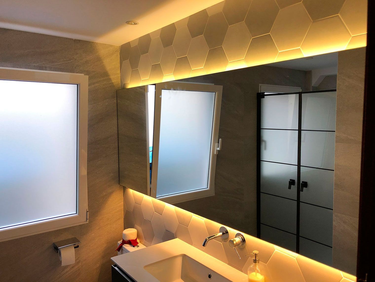 Un baño con un gran espejo y un lavabo.