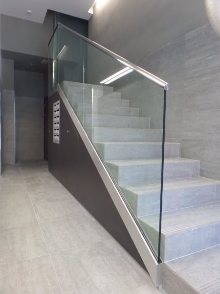 Una escalera con barandilla de cristal en un pasillo.