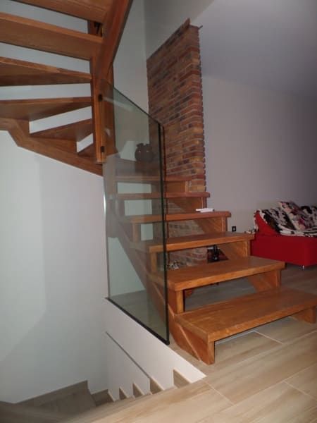 Una escalera de caracol de madera con barandilla de cristal.