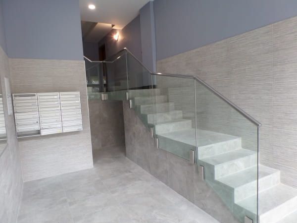 Una escalera con barandilla de cristal en un edificio.